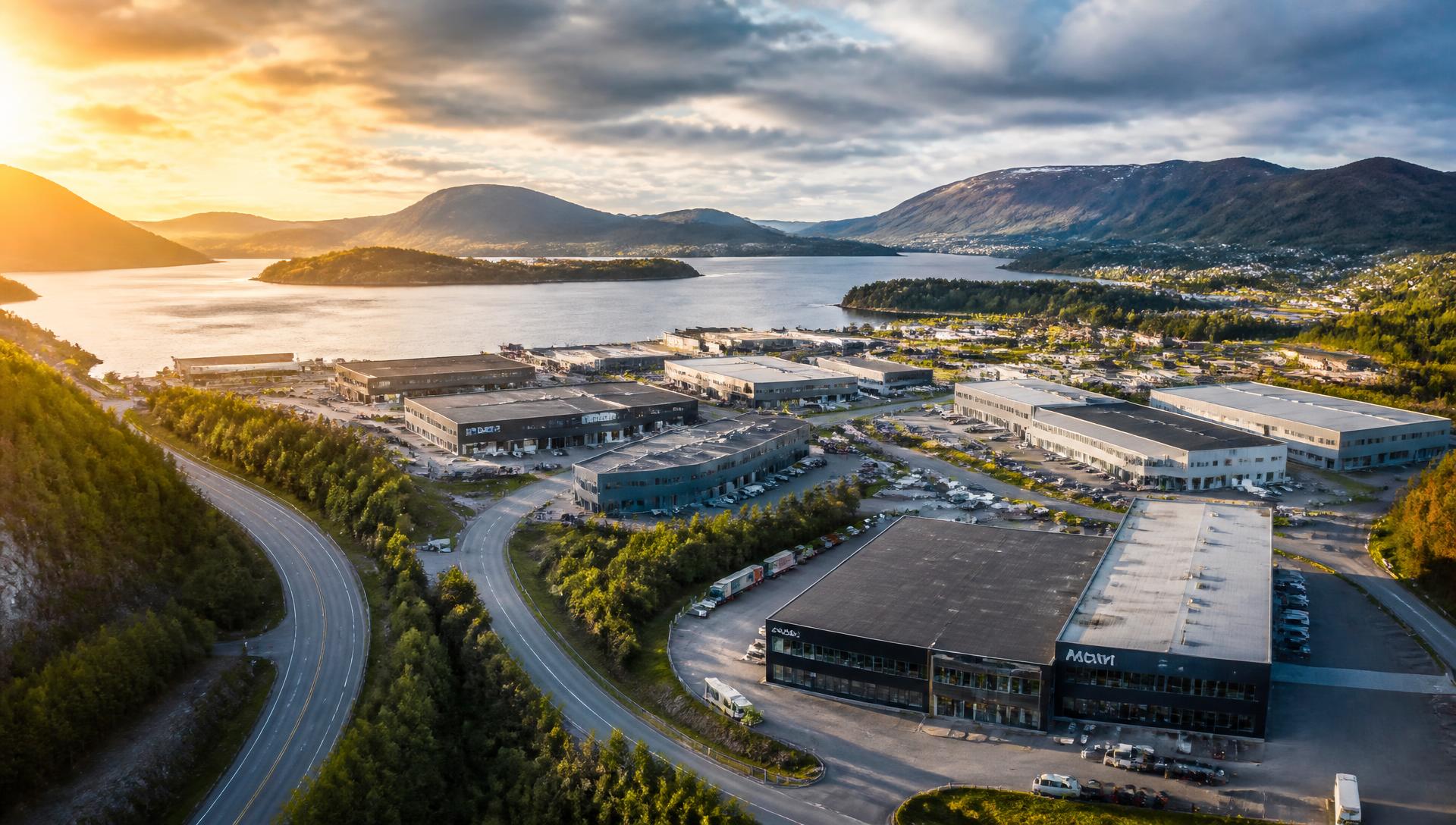 Droneoversikt av næringsområde ved fjord og fjell i solnedgang